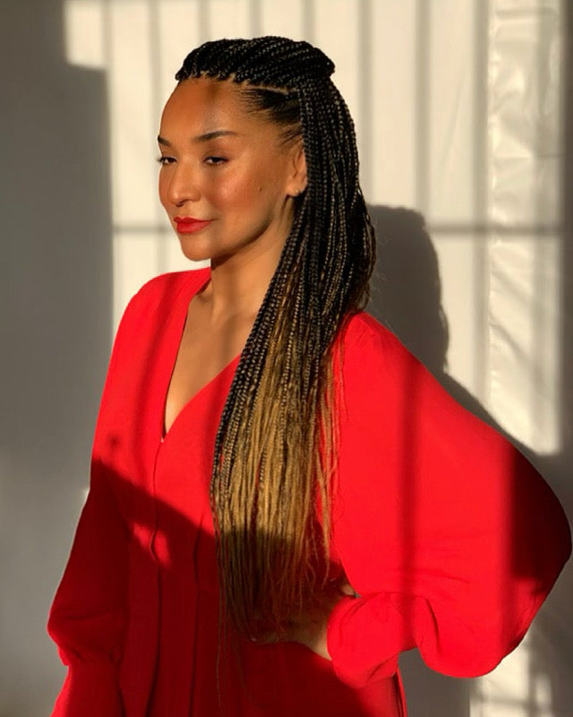 Ego Iwegbu - CEO and Cofounder of The Good Mineral wearing makeup, a red dress and glowing in the sunlight
